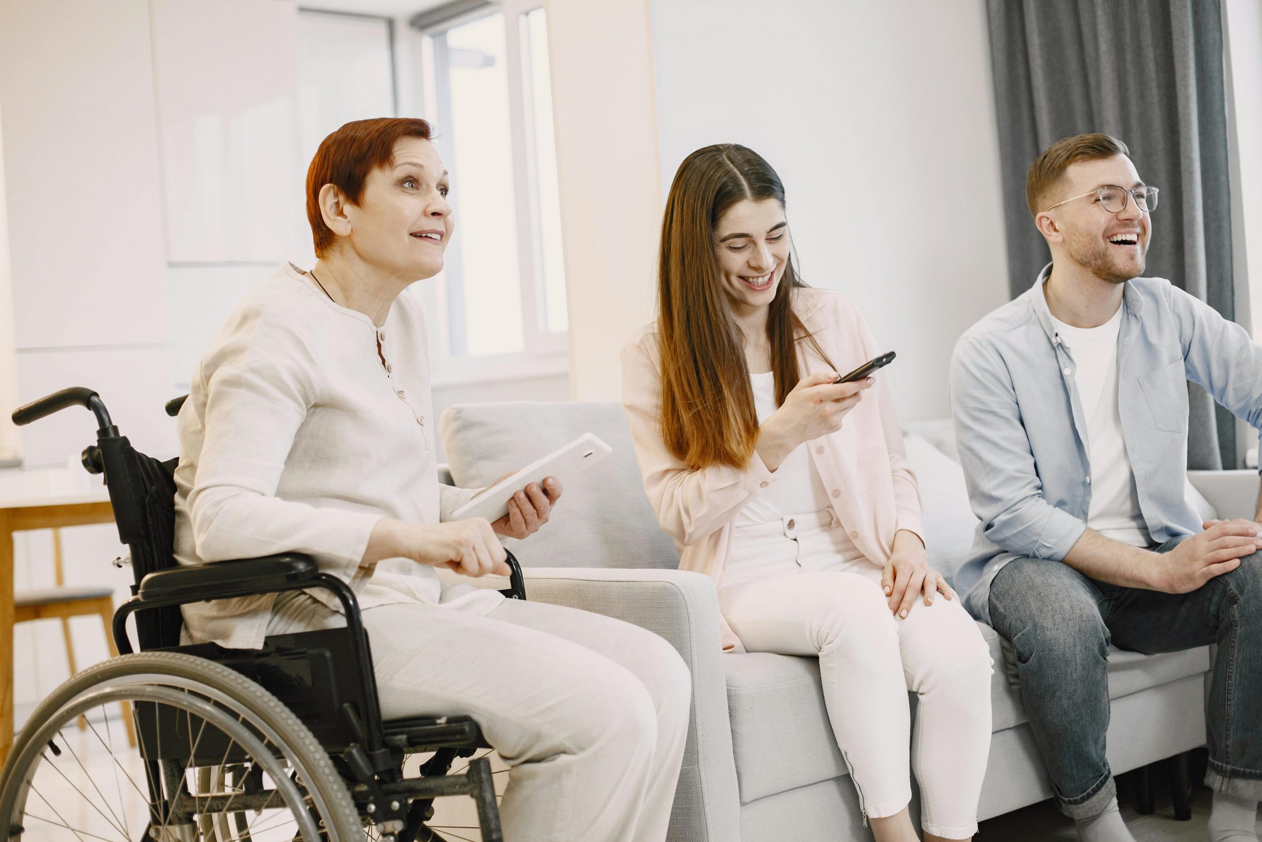 elderly woman in a wheelchair and 2 young adults in the living room
